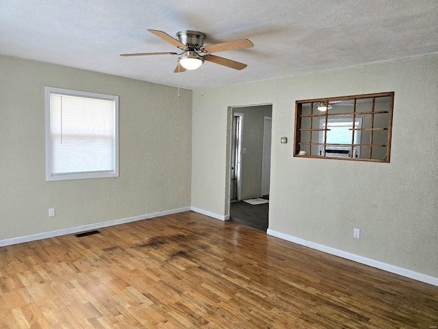 unfurnished room with ceiling fan, wood-type flooring, and a textured ceiling