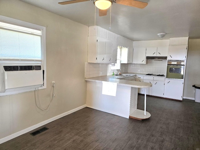 kitchen with a kitchen bar, white cabinets, kitchen peninsula, and oven