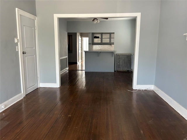 unfurnished living room with ceiling fan, dark hardwood / wood-style flooring, and radiator