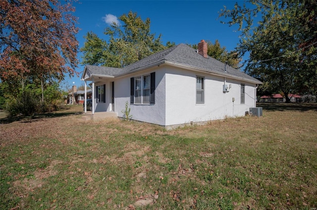 view of property exterior with central AC and a yard