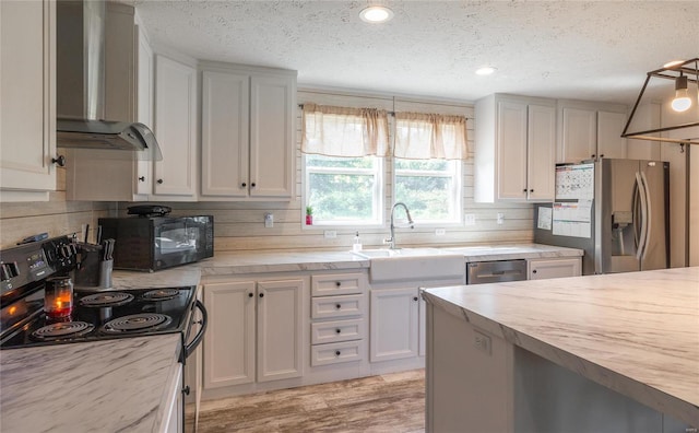 kitchen with backsplash, wall chimney exhaust hood, black appliances, and a textured ceiling