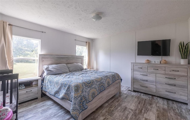 bedroom featuring a textured ceiling, multiple windows, and dark hardwood / wood-style floors