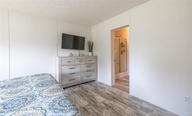 bedroom featuring light hardwood / wood-style floors, a textured ceiling, and ensuite bathroom