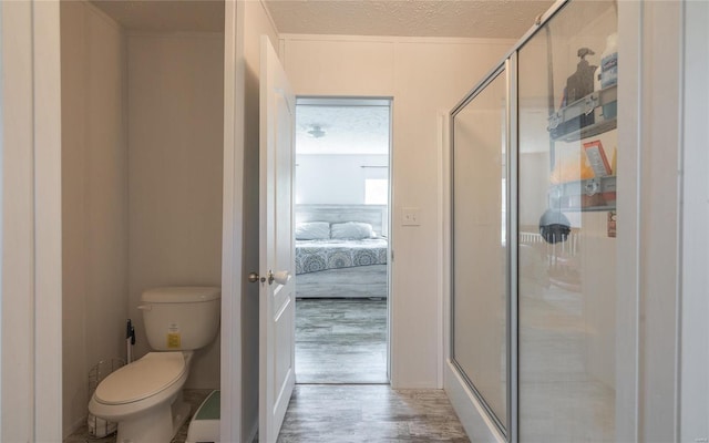 bathroom featuring a textured ceiling, hardwood / wood-style flooring, toilet, and an enclosed shower