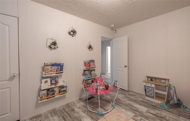 recreation room with hardwood / wood-style floors and a textured ceiling