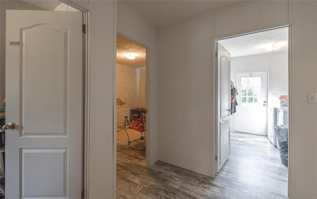 hallway featuring a textured ceiling, light hardwood / wood-style flooring, and washer and clothes dryer