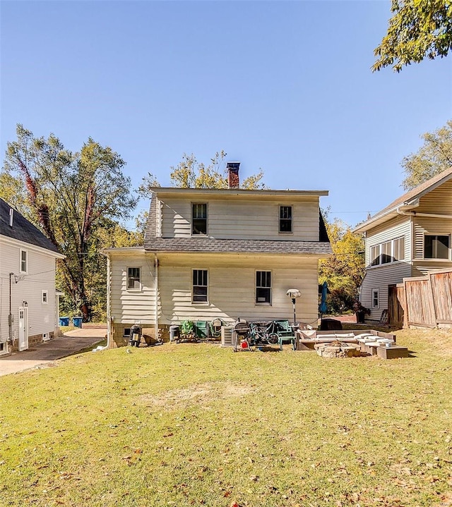 back of house featuring a patio, a lawn, and a fire pit