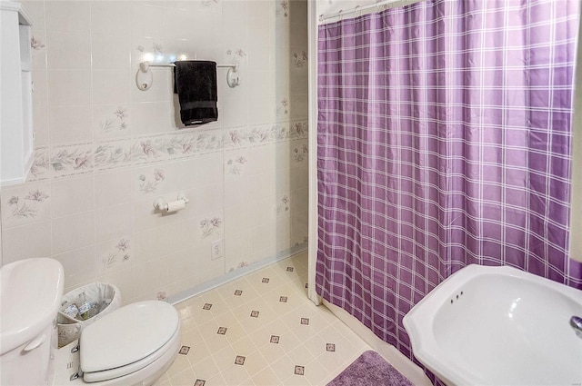 bathroom with tile walls, sink, curtained shower, and toilet