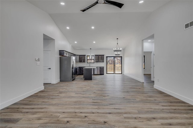 unfurnished living room with high vaulted ceiling, light hardwood / wood-style flooring, and ceiling fan with notable chandelier