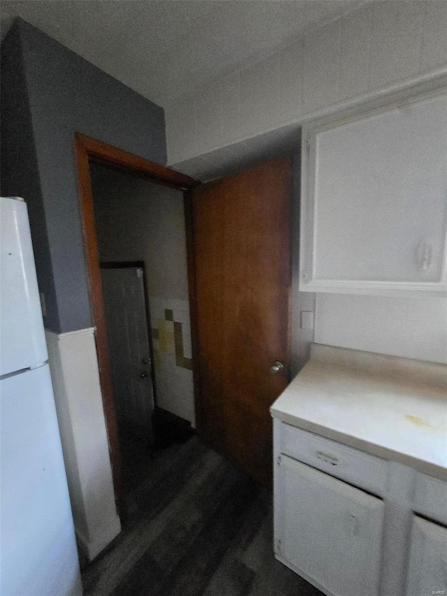 interior space featuring white refrigerator, white cabinetry, and dark hardwood / wood-style floors