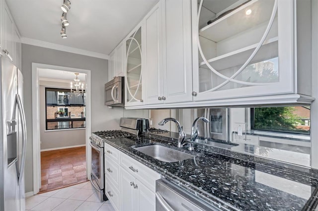 kitchen featuring stainless steel appliances, dark stone countertops, a sink, glass insert cabinets, and a notable chandelier