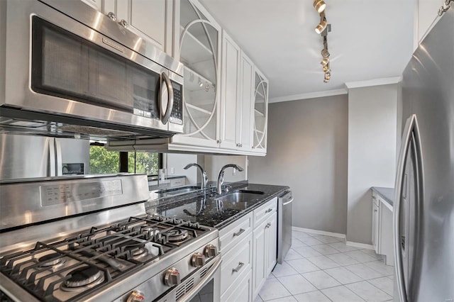 kitchen with stainless steel appliances, dark stone countertops, track lighting, crown molding, and glass insert cabinets