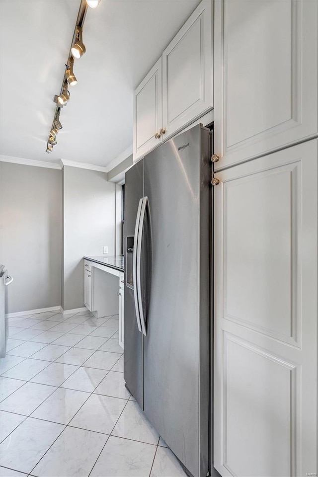 kitchen with white cabinets, stainless steel fridge, baseboards, rail lighting, and ornamental molding