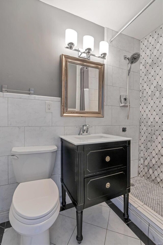 full bathroom with a stall shower, vanity, tile walls, toilet, and tile patterned flooring