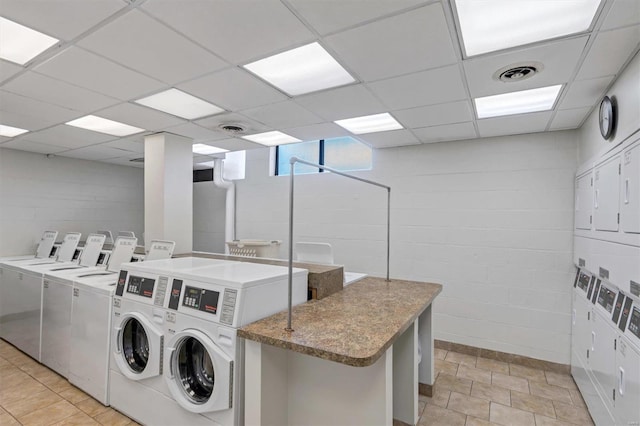 shared laundry area with separate washer and dryer, concrete block wall, stacked washer and clothes dryer, and visible vents