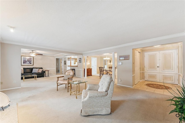 living room with ornate columns, crown molding, light colored carpet, a textured ceiling, and ceiling fan