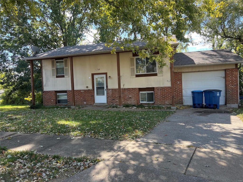 raised ranch featuring a garage and a front yard