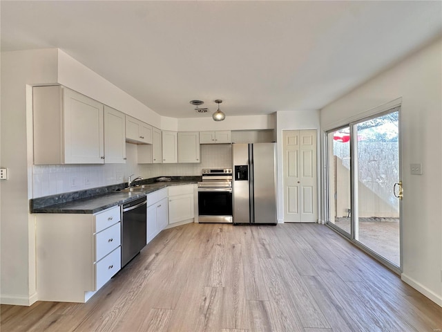 kitchen featuring tasteful backsplash, appliances with stainless steel finishes, sink, white cabinetry, and light hardwood / wood-style flooring