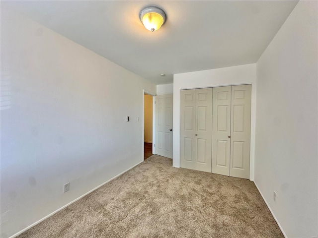 unfurnished bedroom with light carpet and a closet