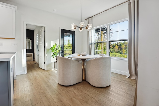 dining area with light hardwood / wood-style floors and an inviting chandelier