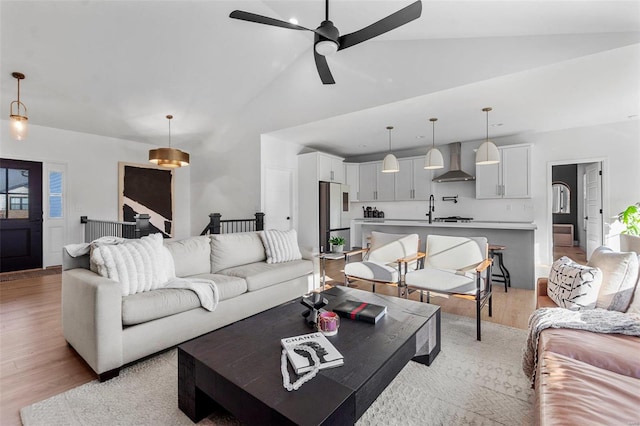 living room featuring ceiling fan, high vaulted ceiling, sink, and light wood-type flooring