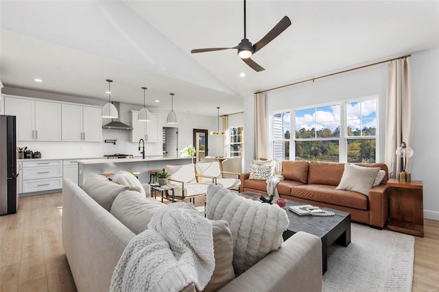 living room with light hardwood / wood-style floors, sink, high vaulted ceiling, and ceiling fan