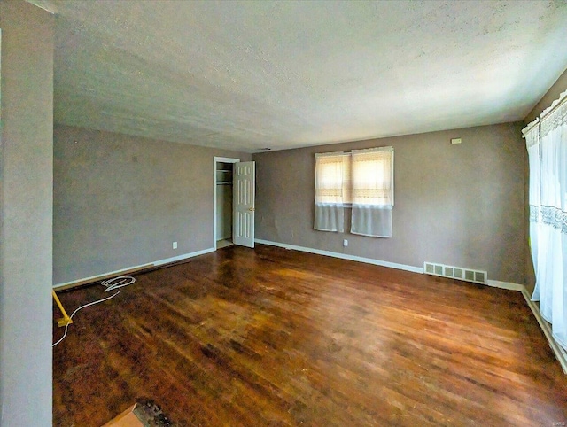 unfurnished room with visible vents, baseboards, a textured ceiling, and wood finished floors