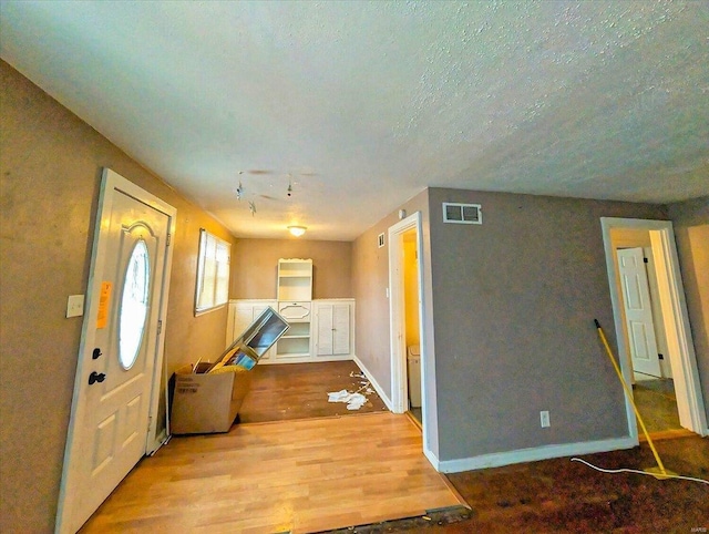 entryway featuring visible vents, a textured ceiling, baseboards, and wood finished floors