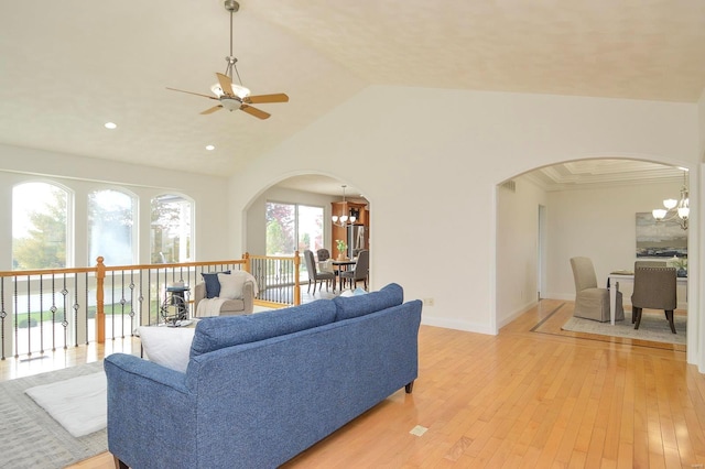 living room featuring lofted ceiling, light hardwood / wood-style flooring, and ceiling fan with notable chandelier