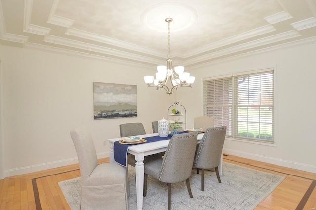 dining space with a notable chandelier, a tray ceiling, wood-type flooring, and crown molding