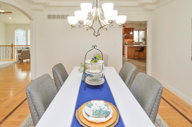 dining area with ornamental molding, ceiling fan with notable chandelier, and light wood-type flooring