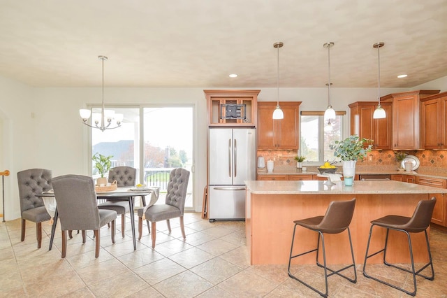 kitchen with stainless steel fridge, decorative light fixtures, and tasteful backsplash