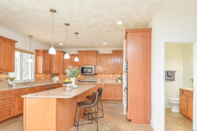 kitchen featuring tasteful backsplash, appliances with stainless steel finishes, a kitchen island, decorative light fixtures, and a breakfast bar area