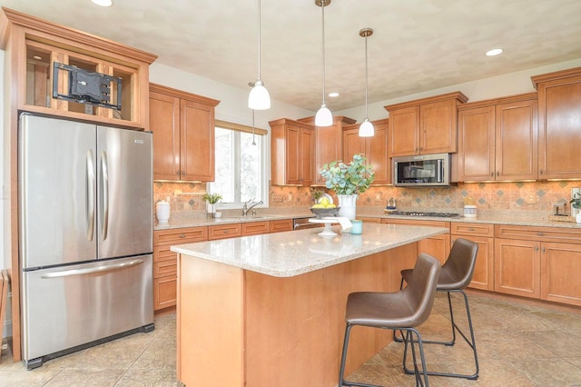 kitchen featuring light stone countertops, appliances with stainless steel finishes, decorative light fixtures, and a kitchen island