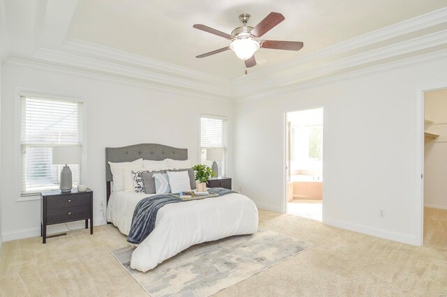 bedroom featuring ceiling fan, a tray ceiling, connected bathroom, carpet floors, and a walk in closet