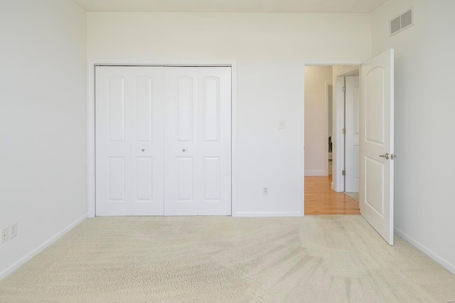 unfurnished bedroom with a closet and light carpet