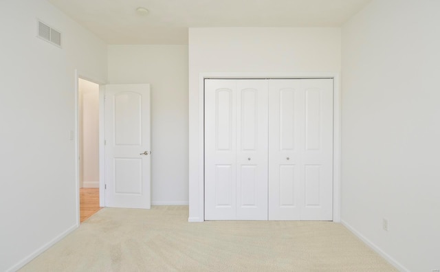 unfurnished bedroom featuring light colored carpet and a closet