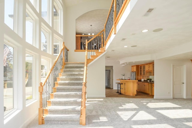 stairs featuring a notable chandelier, carpet flooring, and a wealth of natural light