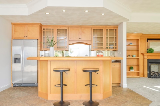 kitchen featuring ornamental molding, a fireplace, stainless steel refrigerator with ice dispenser, and a kitchen bar