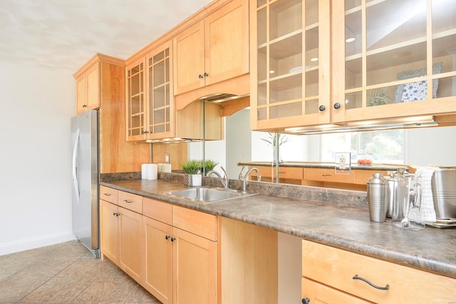 kitchen with sink, light brown cabinets, light tile patterned floors, and stainless steel refrigerator