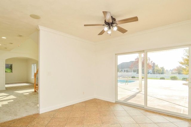 carpeted spare room featuring crown molding, vaulted ceiling, and ceiling fan