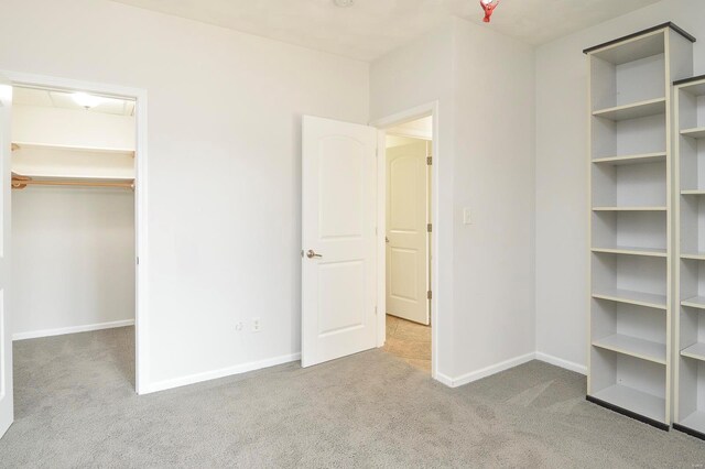 unfurnished bedroom featuring light carpet and a walk in closet