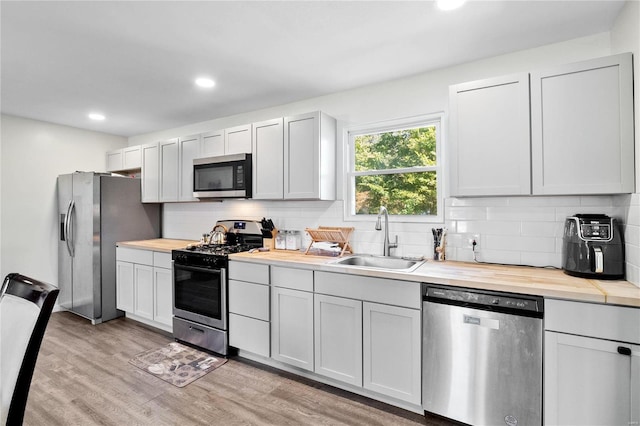 kitchen featuring sink, wood counters, white cabinetry, light hardwood / wood-style floors, and stainless steel appliances