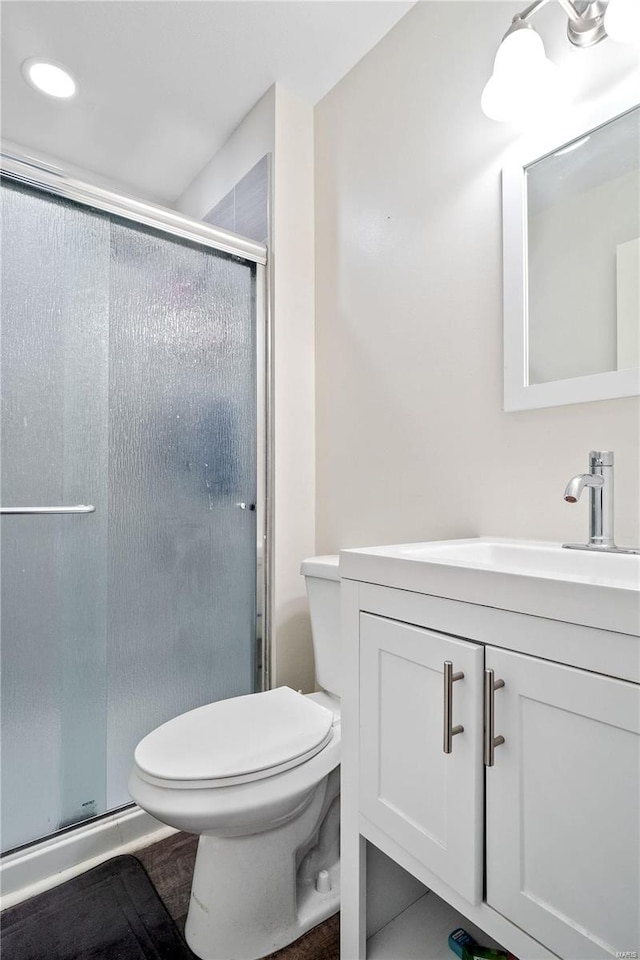 bathroom featuring toilet, a shower with shower door, and vanity