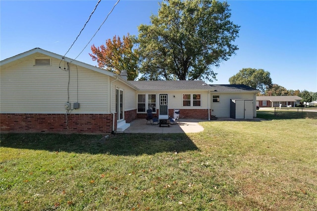 rear view of property featuring a patio area, a storage unit, and a lawn