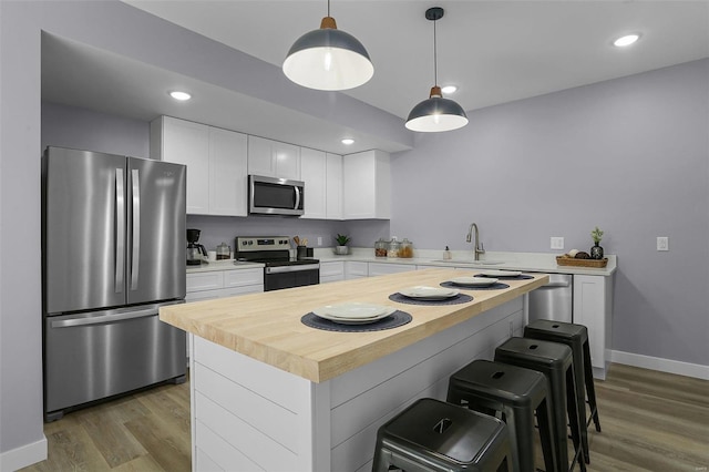 kitchen featuring dark hardwood / wood-style floors, stainless steel appliances, sink, pendant lighting, and white cabinets