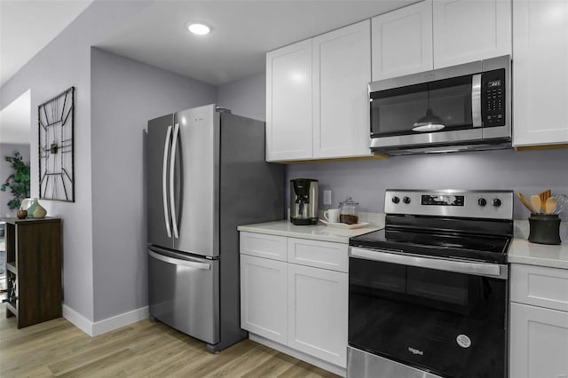 kitchen with light hardwood / wood-style floors, stainless steel appliances, and white cabinets