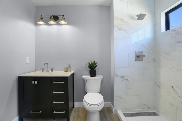 bathroom with vanity, hardwood / wood-style floors, a tile shower, and toilet