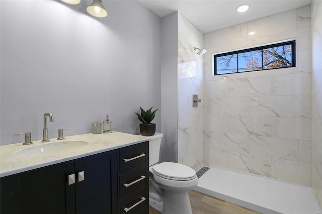 bathroom with vanity, tiled shower, hardwood / wood-style flooring, and toilet