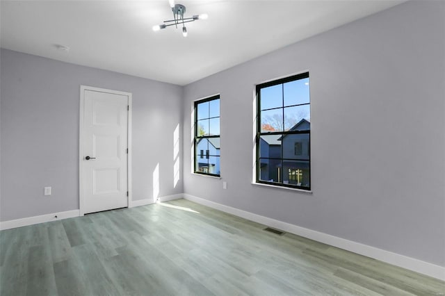 unfurnished room featuring light hardwood / wood-style flooring and a notable chandelier